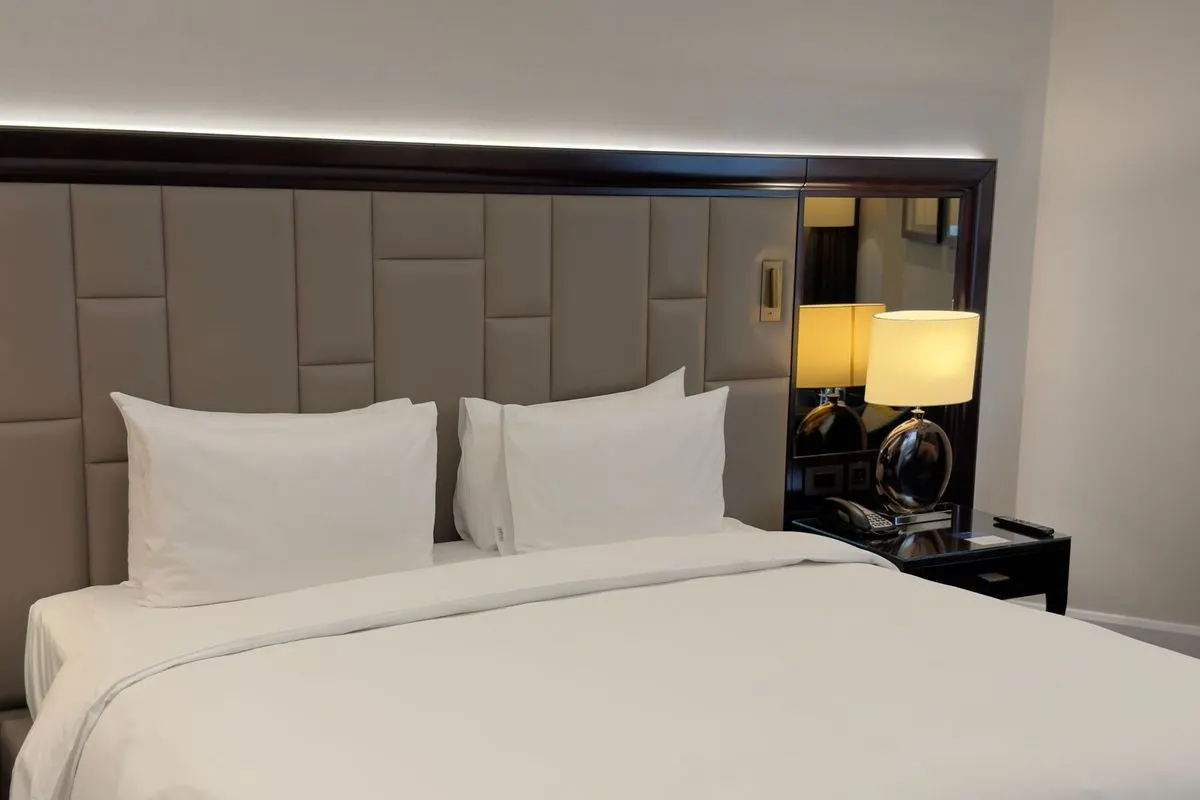 Cama king size com roupa de cama branca em quarto amplo